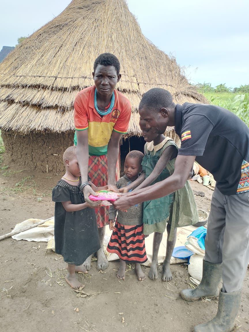 Field officer formally handing over a packet of improved maize seed to a grandmother and her family