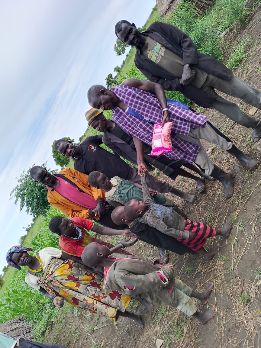Seed handover to a mother and her young children at their thatched homestead
