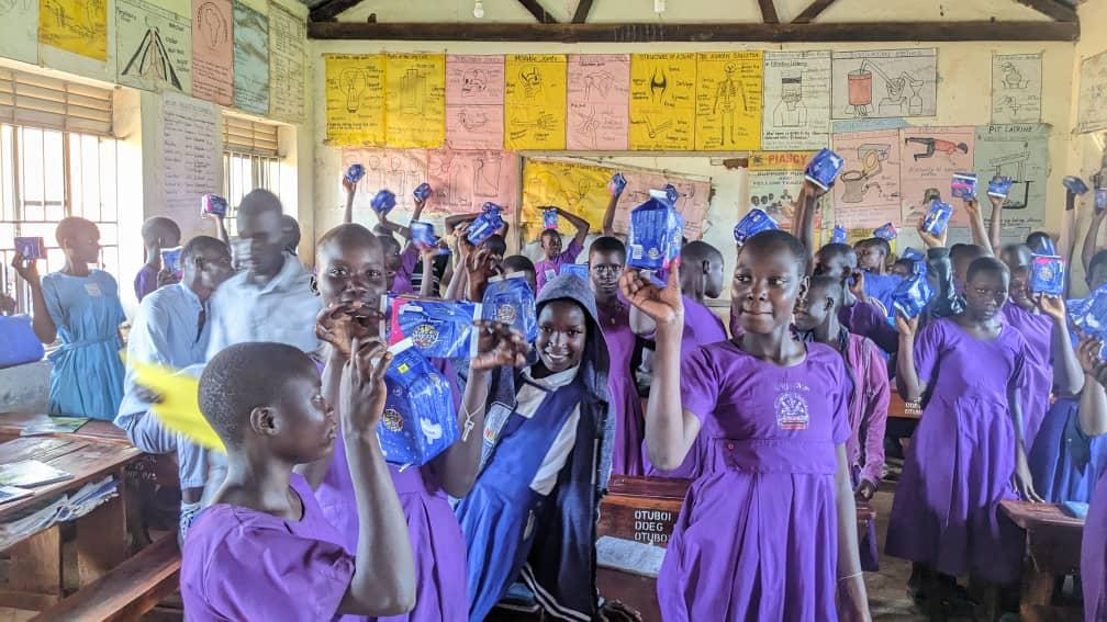 Team leader Samuel Opio with a student during distribution, surrounded by participating girls