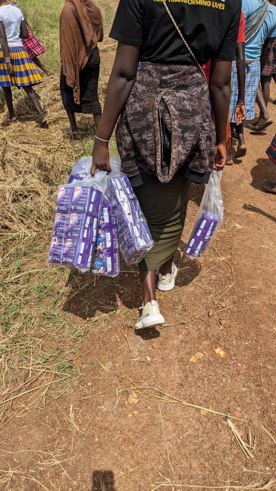 Community women and girls queuing to receive sanitary pads during open-air distribution