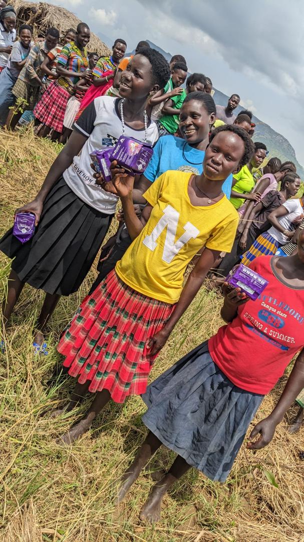 Team member carrying bulk supplies of sanitary pads for community distribution in Napak