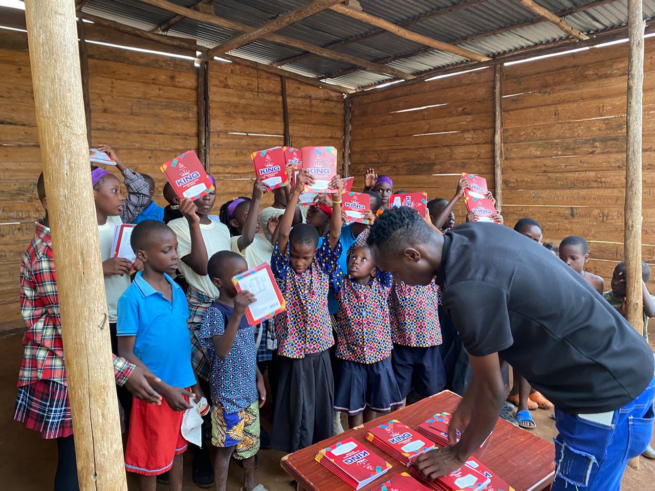 Asili Caring Hand team member distributing exercise books from the stocked distribution table