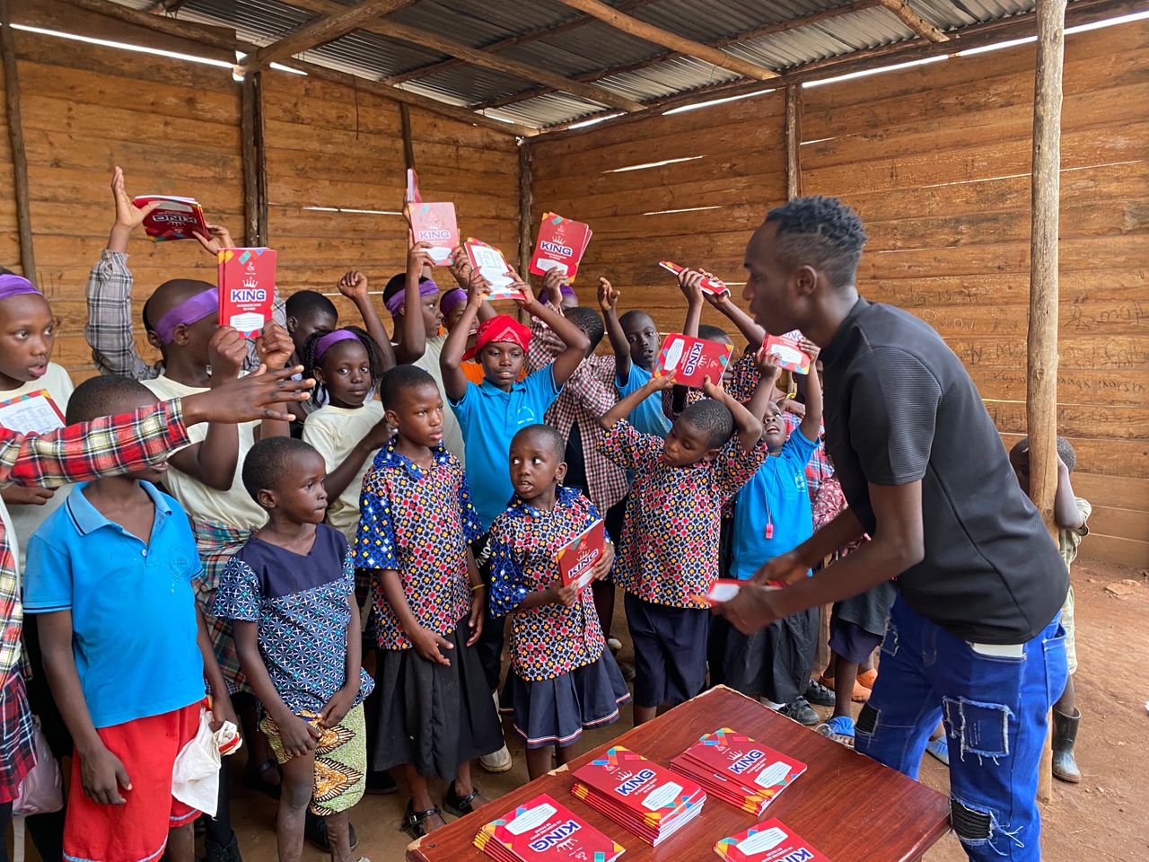 Team member handing out exercise books directly to waiting children