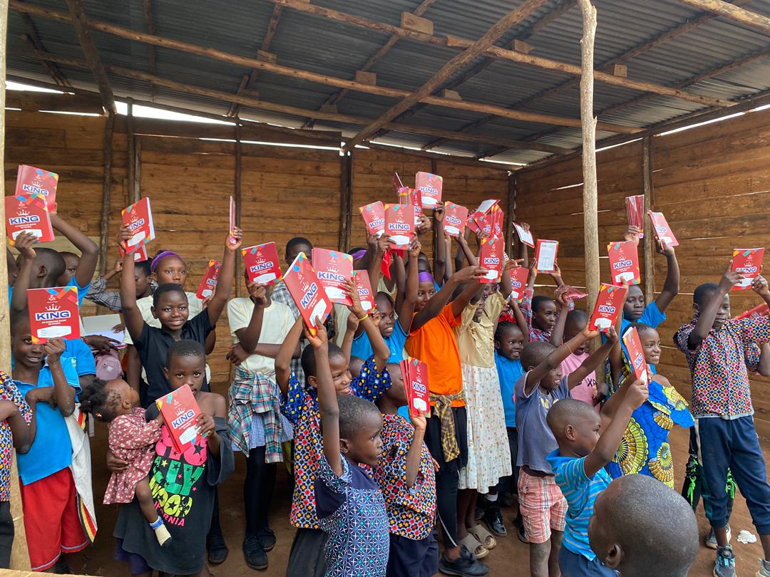 Celebration after distribution — children lifting their exercise books in joy