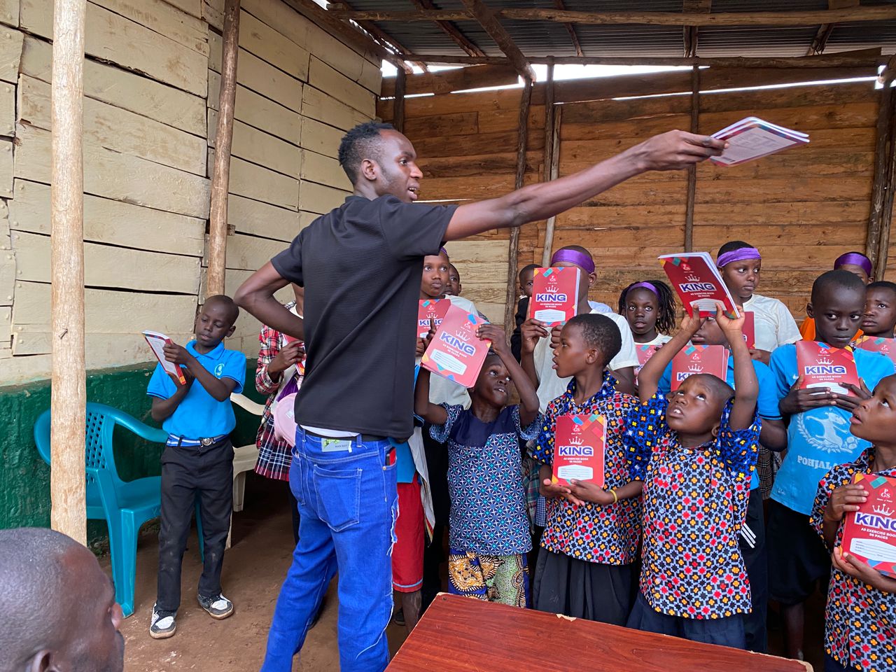 Team member distributing stationery items including pencils to pupils