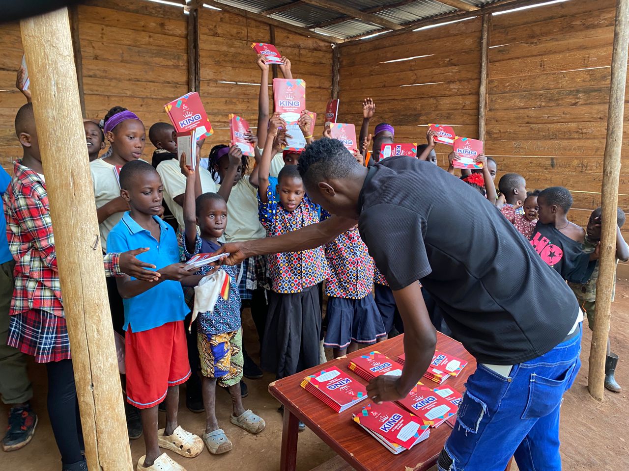 Pupil receiving school stationery and exercise book from team leader Peter Kanakulya